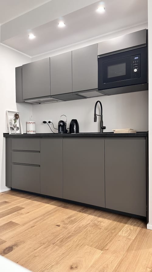 Moderna cucina con mobili grigia, microonde nero e pavimento in legno all'hotel Pellicceria Superior di Genova