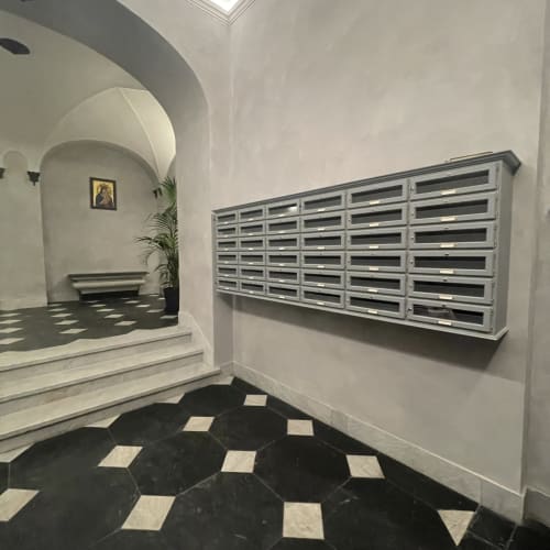 Ingresso e corridoio dell'hotel Pellicceria Superior a Genova con cassette postali e pavimento a piastrelle geometriche