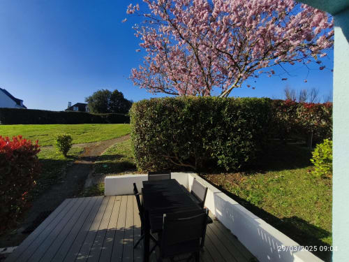 Terrasse avec vue sur jardin et table de salle à manger à l'appartement Loc'Maria Belle Île en Mer, fleurs printanières en arrière-plan