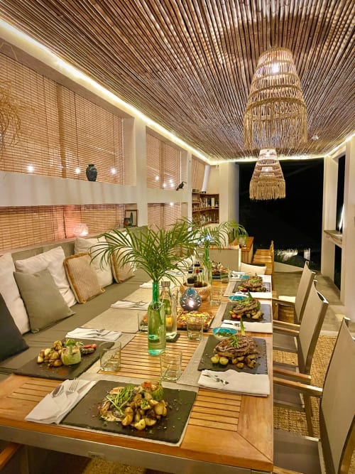Zone de restauration élégante à l'Organica Yoga Shelter à Paquera avec accents en bois, luminaires suspendus tissés et repas dressés