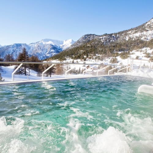 Piscine chauffée en plein air des Tanières de Montgenèvre avec montagnes alpines et paysage enneigé