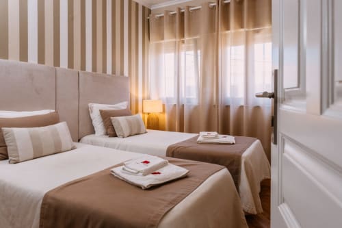 Quarto duplo no hotel Casa da Praia em Zambujeira do Mar com papel de parede listrado, cabeceira bege e iluminação acolhedora