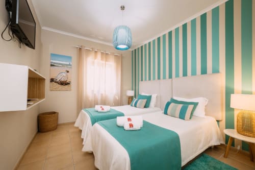 Quarto duplo no hotel Casa da Praia em Zambujeira do Mar com paredes listradas, detalhes em verde-azulado e móveis modernos