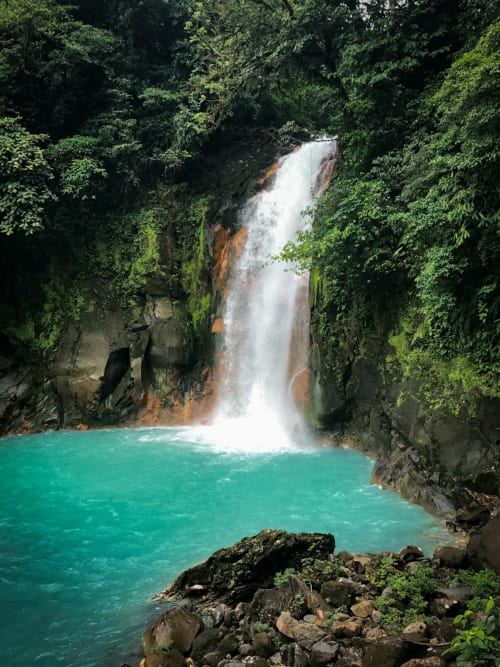 Turquoise waterfall pool surrounded by lush jungle at Organica Yoga Shelter, Paquera, Costa Rica