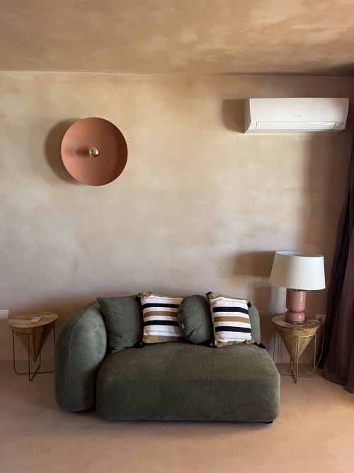 Sala moderna de Formentera Especial con sofá curvo verde, reloj de pared rosa, aire acondicionado blanco y rayas