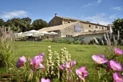 La Maison D'ambrine B&B in Chamaret met stenen gebouw, verzorgde gazons, paarse bloemen en buitenzitplaatsen