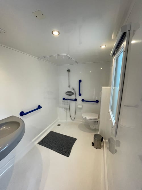 Salle de bains accessible aux fauteuils roulants au Camping La Lézardière avec barres d'appui, douche accessible et toilettes à La Valette du Var