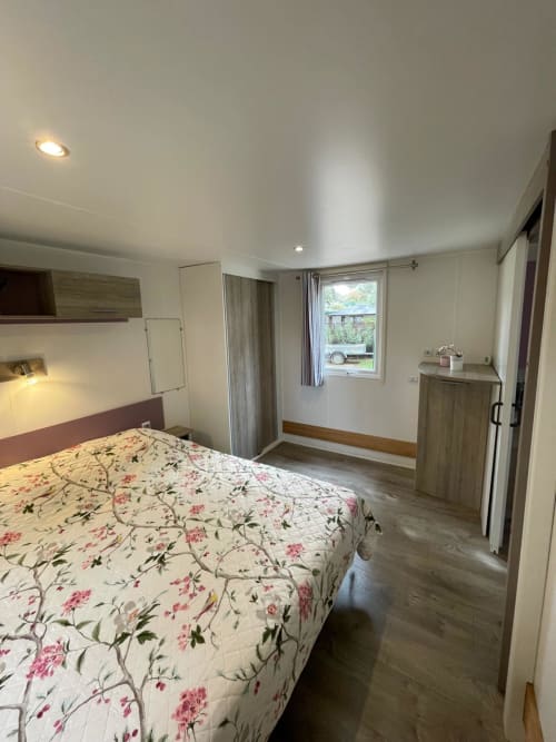 Chambre moderne et lumineuse au Camping La Lézardière avec lit queen-size, TV, vue montagne et mobilier en bois