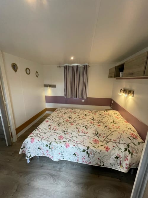 Chambre spacieuse du Camping La Lézardière avec lit queen-size, parure florale et vue sur les montagnes à La Valette du Var