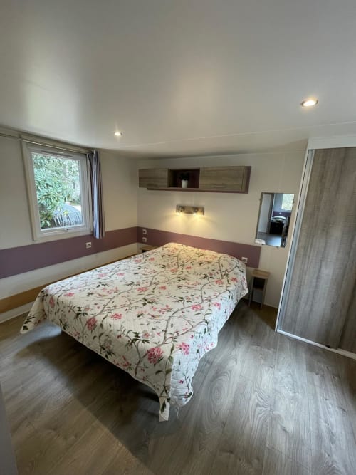 Chambre moderne du Camping La Lézardière avec lit queen-size, parquet et vue sur les montagnes