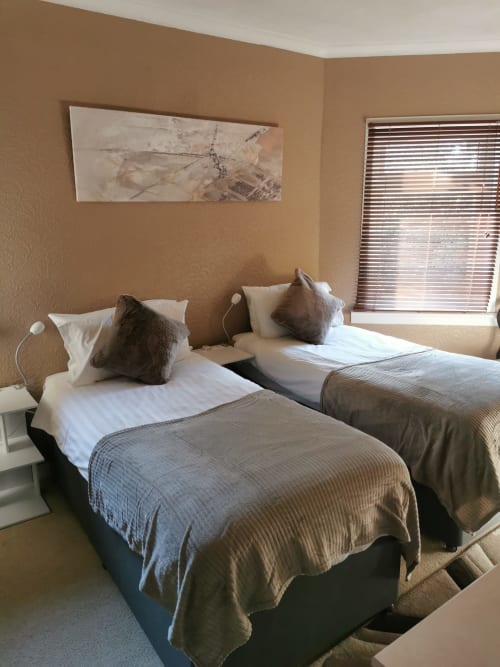 Twin bedroom at Arrochoile B&B Glasgow with two single beds, white linens, brown pillows, and neutral décor