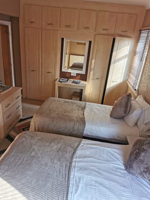 Spacious double or twin bedroom at Arrochoile B&B Glasgow with two beds, wooden wardrobes, vanity mirror, and windows with