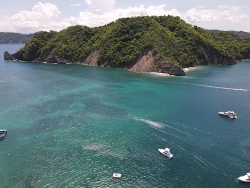 Lush forested island with turquoise waters and boats at Organica Yoga Shelter, Paquera, Costa Rica