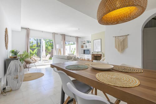 Modern open-plan dining and living area in Marbella beachside townhouse with wooden table, garden views, and bohemian decor