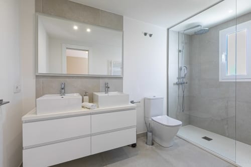 Modern bathroom in Marbella beachside townhouse with dual sinks, rainfall shower, and contemporary fixtures