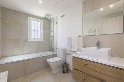 Modern bathroom in Marbella beachside townhouse with double vanity, glass shower, and neutral tile finishes