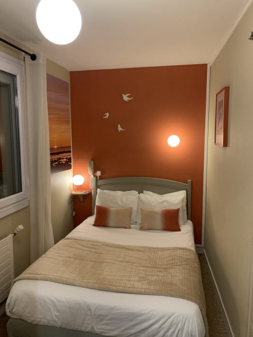 Cozy single bedroom at Hôtel Maison Richet with terracotta accent wall, white bedding, and warm lighting in Les