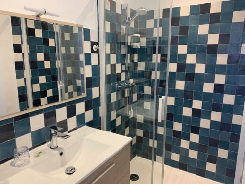 Modern bathroom at Hôtel Maison Richet with teal and cream checkered tiles, walk-in shower, and white vanity sink