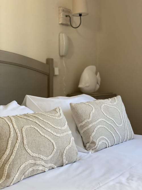 Bedroom at Hôtel Maison Richet with decorative beige pillows on white bedding and wall-mounted amenities