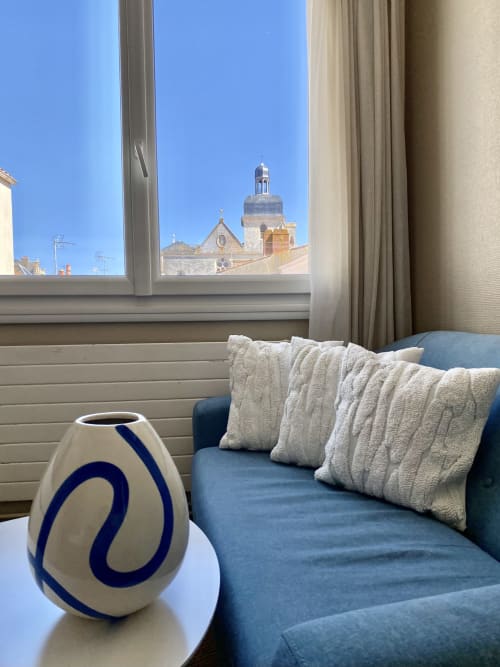 Suite at Hôtel Maison Richet with blue sofa, cream pillows, and view of Les Sables-d'Olonne church tower