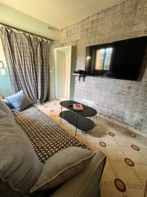 Modern hotel room at Saint Martin in Ollioules with TV, patterned wallpaper, curtains, and black table