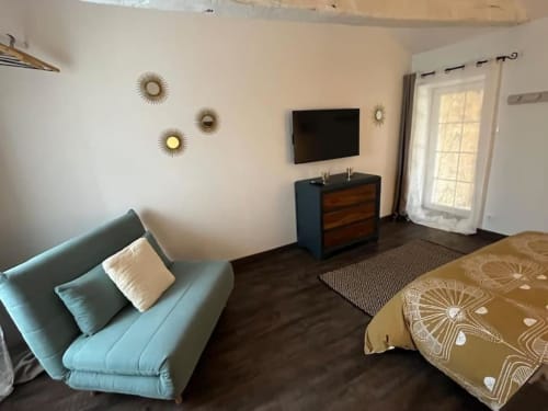 Bedroom with television, bed, chair, and drawer | La Petite Maison: Cozy Charm for an Intimate Escape