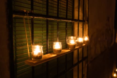 Frascos de cristal iluminados por velas en la ventana de la posada rural Fuente Vieja, Arbancón España, con cálida iluminación ambiental