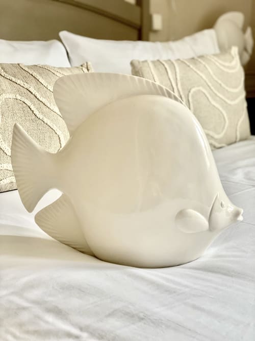 White ceramic fish-shaped decorative bowl on bed with pillows at Hôtel Maison Richet, Les Sables-d'Olonne