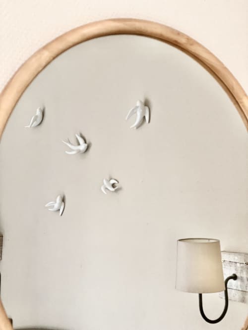 Minimalist wall decor with white ceramic leaf sculptures and wooden-framed mirror in Hôtel Maison Richet bedroom