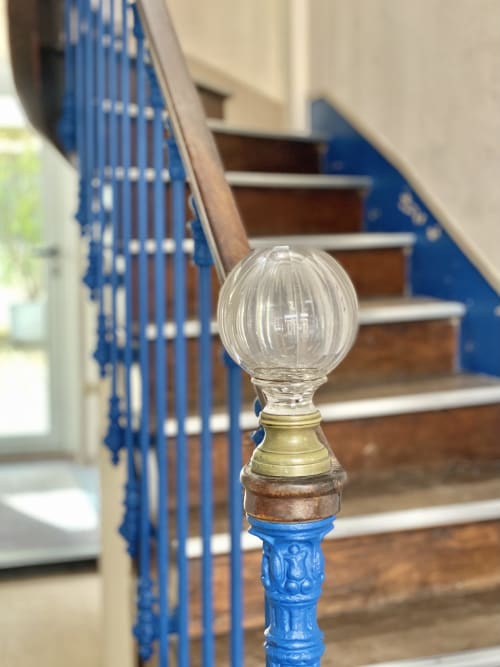 Ornate blue staircase finial at Hôtel Maison Richet, Les Sables-d'Olonne, with wooden stairs and railing in background