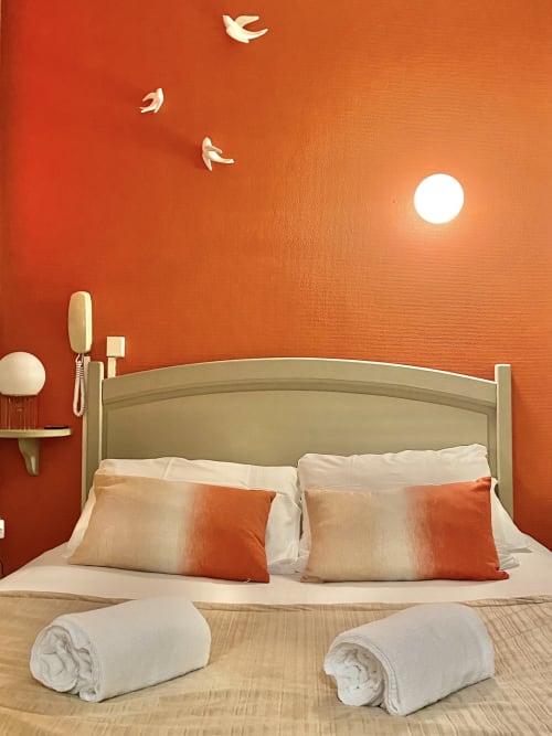 Modern bedroom at Hôtel Maison Richet with terracotta walls, neutral bed, and minimalist sunset decor in Les Sables-d'Olonne