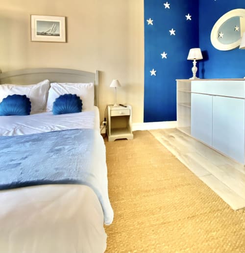 Coastal-themed suite at Hôtel Maison Richet with blue accent wall, white furniture, and starry moon decor