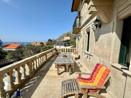 Terraza con vistas al mar de la villa Vila Arume en Baiona con mesa de comedor, tumbonas y vistas al Mediterráneo