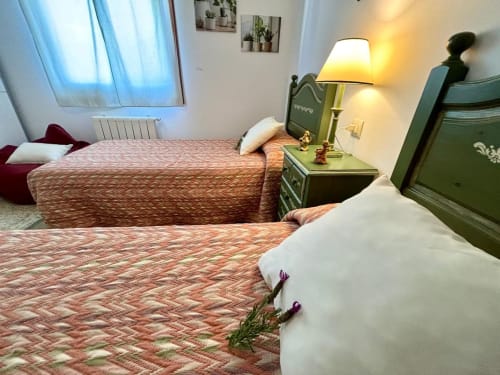 Camas gemelas con colchas estampadas en la casa rural Casa Caeiro, Baiona, con mesita de noche verde e iluminación cálida