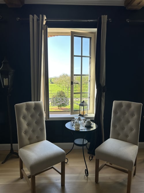 Suite élégante au Clos Mahiel avec fauteuils capitonnés, vue sur la campagne par de grandes fenêtres, Saint-Romain-de-Colbosc France. Chambre Inès-Style.