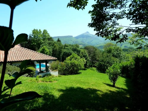 Le jardin verdoyant de Villa Ongizatea avec pool house, pelouse et vue sur les montagnes à Urrugne, France