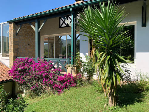Porche de la maison d'hôtes Villa Ongizatea avec bougainvillée magenta, palmier et vue sur les montagnes à Urrugne