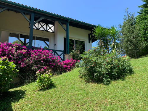 Le gîte Villa Ongizatea à Urrugne : chalet de charme aux finitions vertes, bougainvillées magenta et jardins soignés
