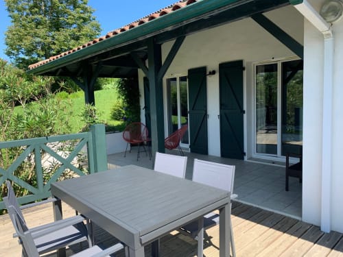Villa Ongizatea cottage terrace in Urrugne with dining table, green shutters, and mountain views