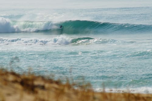 Surfista deslizándose en las olas turquesas de la playa de Urrugne cerca del alojamiento Villa Ongizatea en Francia