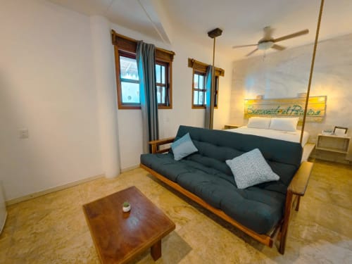 Habitación moderna del Hotel 40 Cañones en Mahahual con futón oscuro, muebles de madera y cama