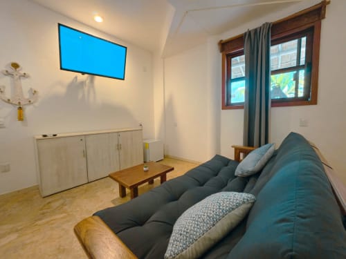 Acogedor cuarto en Hotel 40 Cañones de Mahahual con sofá turquesa, muebles de madera y televisor de pared