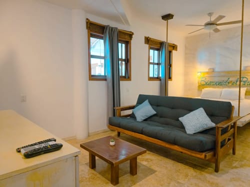 Habitación moderna del Hotel 40 Cañones en Mahahual con sofá de madera, mesa de café y vista al patio interior