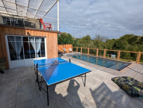 Espace extérieur du gîte La Grange des Colporteurs avec table de ping-pong, piscine, terrasse en bois, balcon aménagé et vue sur la nature. Idéal pour des vacances actives et relaxantes en Charente.