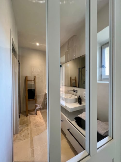 Salle de bain moderne de Provence Km28 à Gordes avec double vasque, grand miroir et porte-serviettes en bois