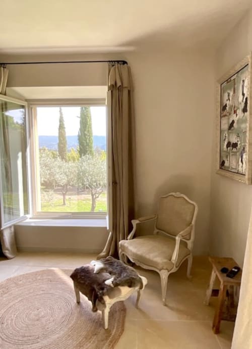 Élégant salon du Provence Km28 à Gordes avec vue sur les montagnes et cyprès visibles par les grandes fenêtres