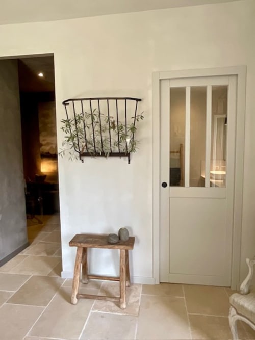 Entrée Provence Km28 à Gordes avec banc rustique, plante en pot et porte blanche menant à la chambre Les Cyprès