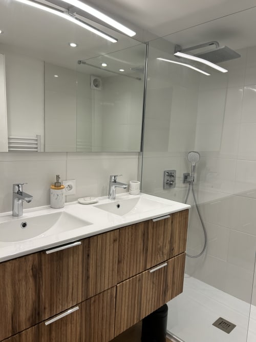 Salle de bain moderne de l'hôtel Mazet Cavalaire avec double vasque, douche à l'italienne et mobilier en bois chaleureux