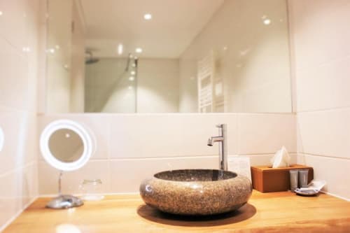 Bathroom with large mirror and sink with toiletries | Spacious and Elegant – The Family Loft Suite Awaits You