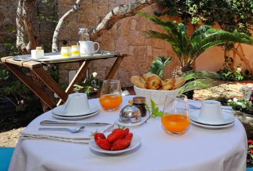 Petit-déjeuner élégant en terrasse à Villa Marina Di Cavu à Bonifacio avec viennoiseries, fraises et jus d'orange